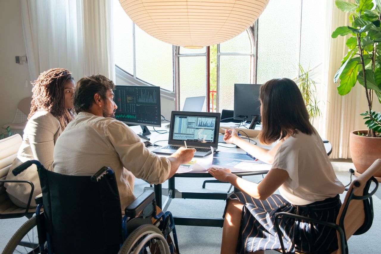 Team of diverse coworkers discussing charts and graphs at a bright, modern office table.